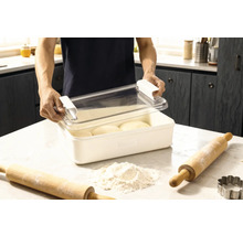 Teigbehälter mit Deckel und zwei Nudelhölzern sowie Mehl auf einer Küchenoberfläche