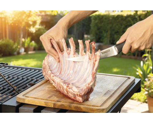 Zubereitung von Lammkarree auf einem Holzbrett mit einem Tenneker Messer im Garten.