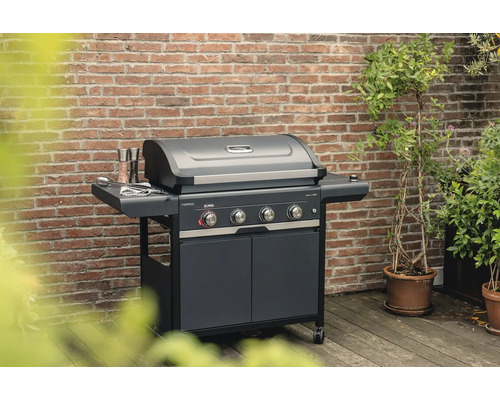 Gasgrill mit vier Brennern und Unterschrank vor einer Backsteinmauer