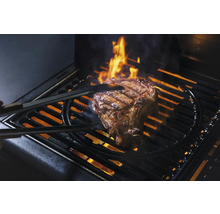 Ein Steak wird auf einem Grill mit einer Grillzange gewendet
