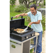 Mann bereitet Pizza auf einem CampinGaz Grill im Garten zu.