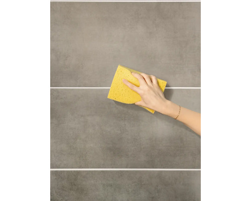 Hand wischt mit einem Schwamm über Fliesen.