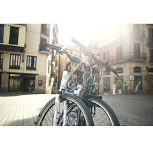 Zwei Fahrräder stehen in einer städtischen Umgebung vor Gebäuden.