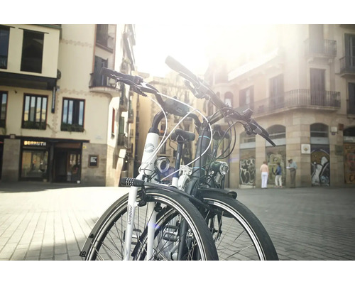 Zwei Fahrräder stehen in einer städtischen Umgebung vor Gebäuden.