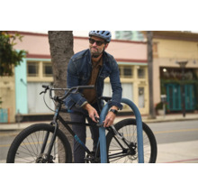 Mann schließt Fahrrad mit Zahlenschloss an Fahrradständer an