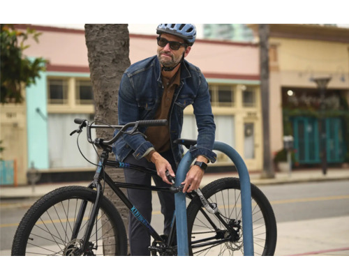 Mann schließt Fahrrad mit Zahlenschloss an Fahrradständer an