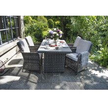 Gartenszene mit Esstisch und vier Korbsesseln mit Auflagen auf einer Steinterrasse