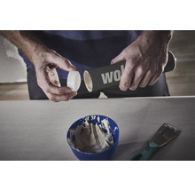 Eine Person öffnet eine Dose mit Spachtelmasse über einer Schüssel mit Spachtelmasse.