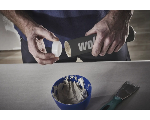 Eine Person öffnet eine Dose mit Spachtelmasse über einer Schüssel mit Spachtelmasse.