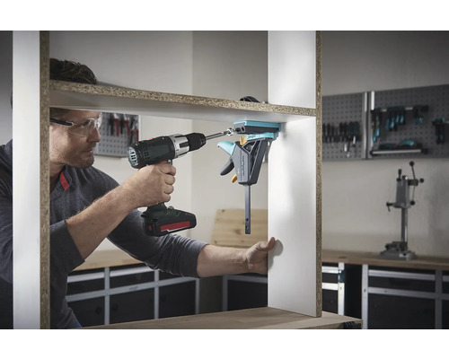 Ein Mann montiert ein Regal mit einem Akku-Bohrschrauber und einer Einhandzwinge.