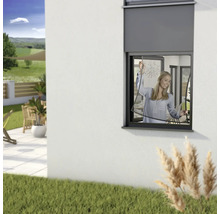 Frau befestigt Insektenschutzgitter am Fenster