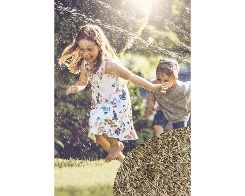 Kinder spielen im Garten unter einem Rasensprenger, Rasensamen im Vordergrund