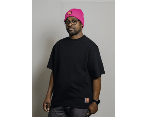 Mann mit Brille, schwarzem T-Shirt und pinkfarbener Mütze