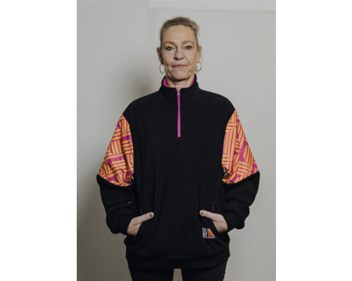Frau trägt eine schwarze Fleecejacke mit geometrischen Mustern an den Ärmeln.