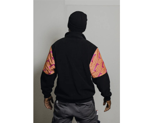 Person trägt eine schwarze Fleecejacke mit gemusterten Ärmeln