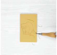 Radiergummi mit Waschbärmotiv wird mit einem Schnitzwerkzeug bearbeitet.