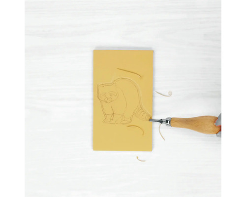 Radiergummi mit Waschbärmotiv wird mit einem Schnitzwerkzeug bearbeitet.