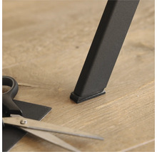 Möbelgleiter unter einem Tischbein und eine Schere zum Zuschneiden