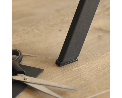 Möbelgleiter unter einem Tischbein und eine Schere zum Zuschneiden