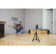 Mann benutzt Laser-Wasserwaage zum Ausrichten eines Regals an einer Wand