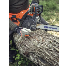 Eine Person sägt mit einer Husqvarna Kettensäge einen Baumstamm.