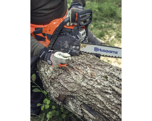 Eine Person sägt mit einer Husqvarna Kettensäge einen Baumstamm.