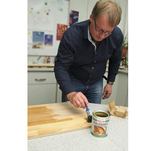 Mann trägt Boots- und Yachtlack auf ein Holzbrett auf