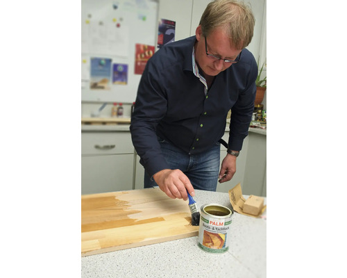 Mann trägt Boots- und Yachtlack auf ein Holzbrett auf