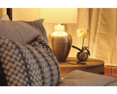 Schlafzimmer mit Nachttischlampe und dekorativer Kunstblume