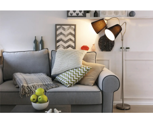 Wohnzimmer-Szene mit Sofa, Kissen und Stehlampe für eine gemütliche Atmosphäre.