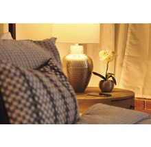 Dekoratives Schlafzimmer mit Lampe, Nachttisch und Kissen