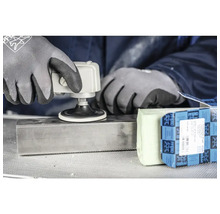 Eine Person verwendet eine Schleifmaschine auf einem Metallstück, zusammen mit Schleifpaste und einer Verpackung der Marke Pferd.