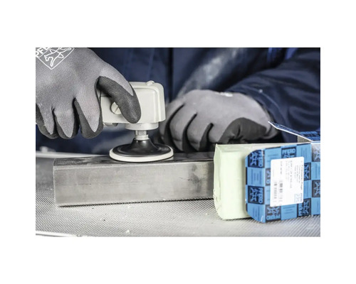 Eine Person verwendet eine Schleifmaschine auf einem Metallstück, zusammen mit Schleifpaste und einer Verpackung der Marke Pferd.