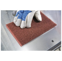 Schleifvlies mit Handschuh auf Metalltisch