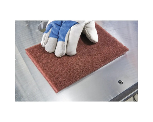 Schleifvlies mit Handschuh auf Metalltisch