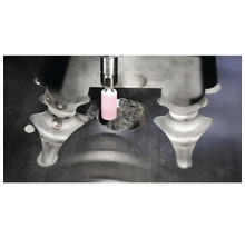 Zylindrischer rosa Schleifstift bei der Bearbeitung eines Werkstücks aus Metall.