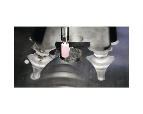 Zylindrischer rosa Schleifstift bei der Bearbeitung eines Werkstücks aus Metall.