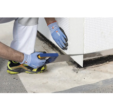 Ein Handwerker sägt eine Dämmplatte mit einer Handsäge zu.