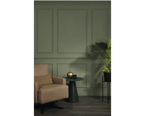 Wohnzimmer mit Sessel, Beistelltisch und Zimmerpflanze vor einer Wand mit Paneelen