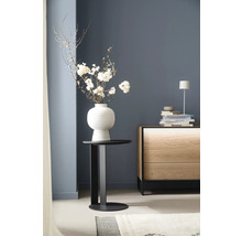 Dekoratives Arrangement mit Blumen in einer Vase auf einem Beistelltisch neben einer Kommode