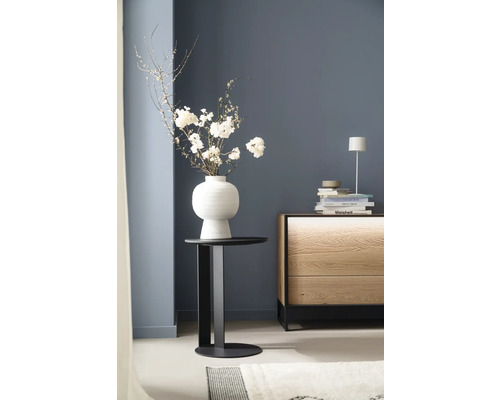 Dekoratives Arrangement mit Blumen in einer Vase auf einem Beistelltisch neben einer Kommode