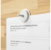 Magnetischer Haken hält eine Bedienungsanleitung an einer Holzoberfläche
