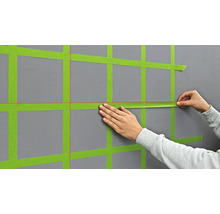 Anbringen von Abdeckband an einer Wand zur Vorbereitung von Malerarbeiten