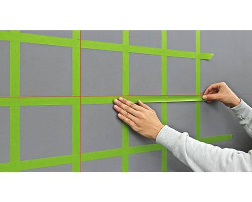 Anbringen von Abdeckband an einer Wand zur Vorbereitung von Malerarbeiten