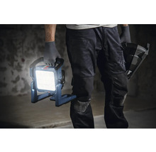 Handwerker hält eine eingeschaltete Bosch Baustellenlampe in der Hand