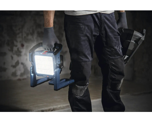 Handwerker hält eine eingeschaltete Bosch Baustellenlampe in der Hand