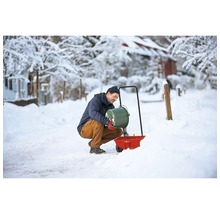 Mann befüllt Streuwagen im Winter mit Streugut