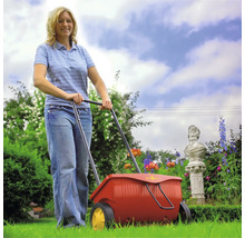 Frau benutzt Streuwagen im Garten