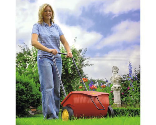 Frau benutzt Streuwagen im Garten