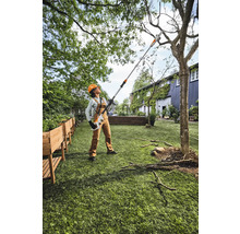 Frau arbeitet mit einer Hochentaster im Garten.